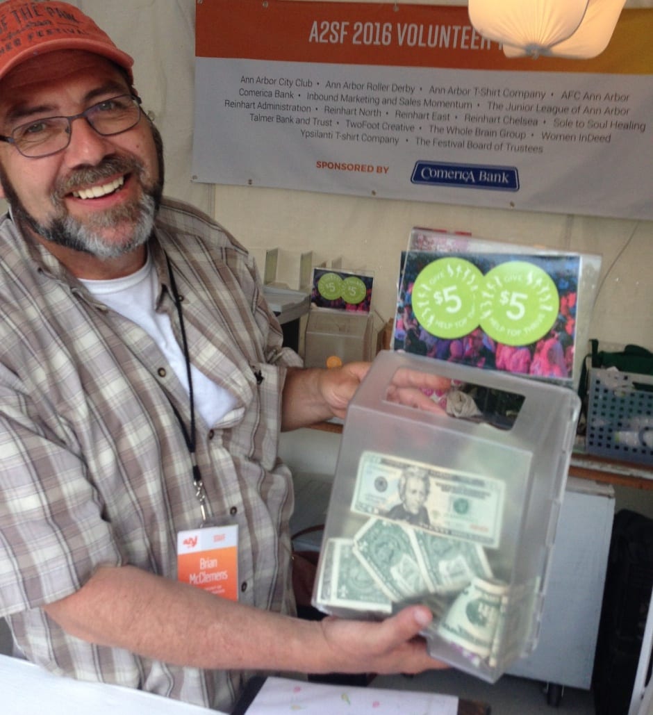 Top of the Park volunteer holding collection box of donations