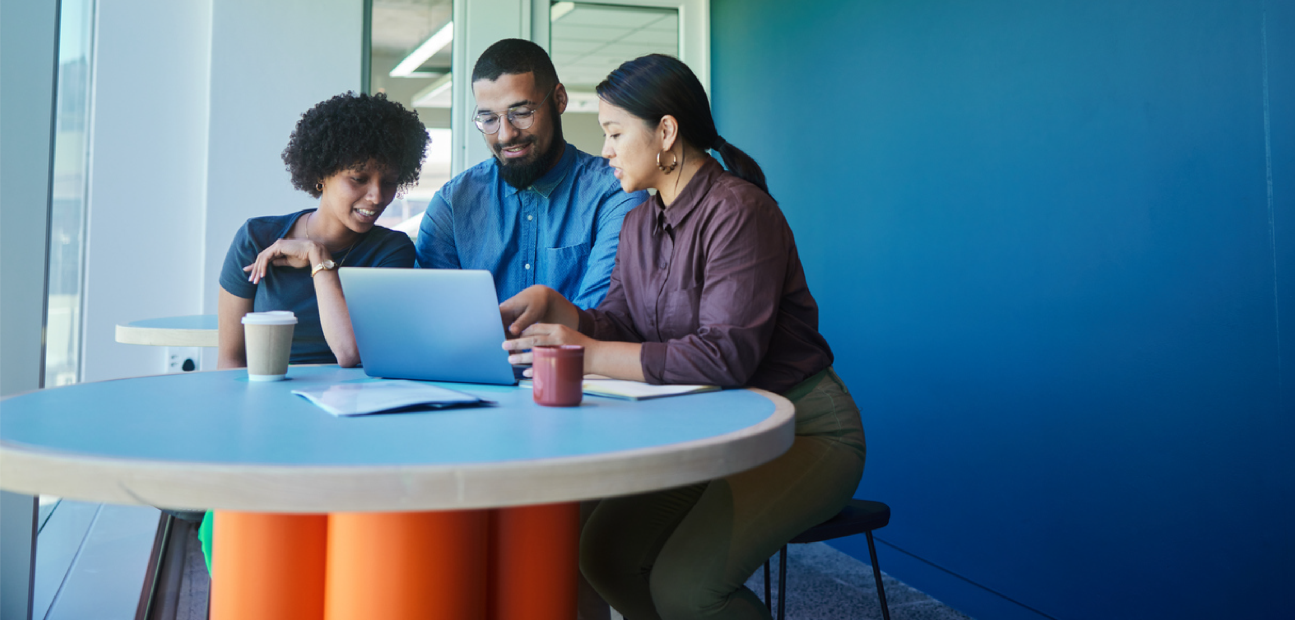 three people looking at one laptop